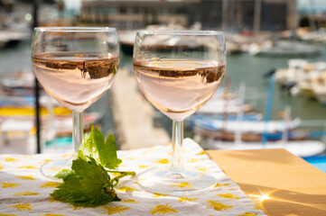 Rose wine in glasses served on outdoor terrace with view on old fisherman's harbour with colourful...