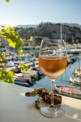 Cold rose wine in glass served on outdoor terrace in sunlights with view on old fisherman's harbour with colourful boats in Cassis, Provence, France