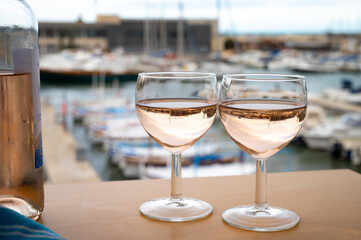 Rose wine in glasses served on outdoor terrace with view on old fisherman's harbour with colourful...