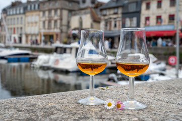Tasting of apple calvados drink in old Honfleur harbour with boats and old houses on background, Normandy, France