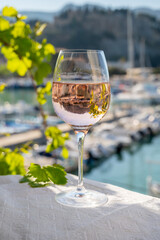Rose wine in glass served on outdoor terrace with view on old fisherman's harbour with colourful boats in Cassis, Provence, France