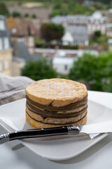 Tasting of yellow livarot cow cheese from Calvados region and view on old houses of Etretat, Normandy, France