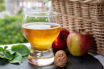 Glass of cold apple cider drink and houses of Etretat village on background, Normandy, France