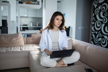 Creative young woman working on laptop in her studio at home  on couch 