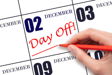 2nd day of December. Hand writing text DAY OFF and drawing a line on calendar date 2 December....