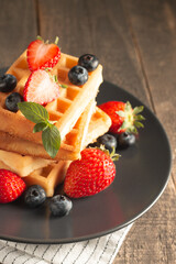 Fresh homemade food of berry Belgian waffles with honey, chocolate, strawberry, blueberry, maple syrup and cream. Healthy dessert breakfast concept with coffee