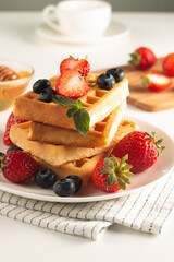 Fresh homemade food of berry Belgian waffles with honey, chocolate, strawberry, blueberry, maple syrup and cream. Healthy dessert breakfast concept with coffee