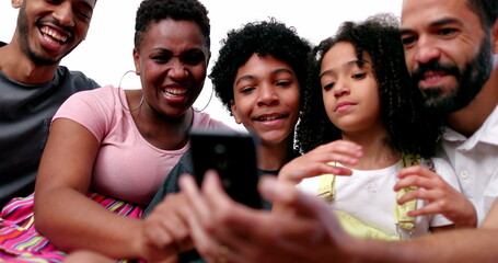 Happy mixed race family looking at phone device laughing and smiling