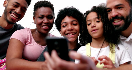 Happy mixed race family looking at phone device laughing and smiling