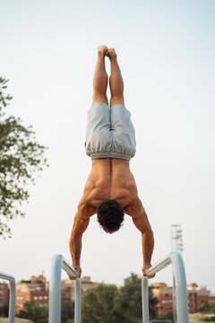 Strong sportsman balancing on parallel bars