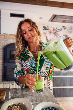 Woman pouring smoothie into glass
