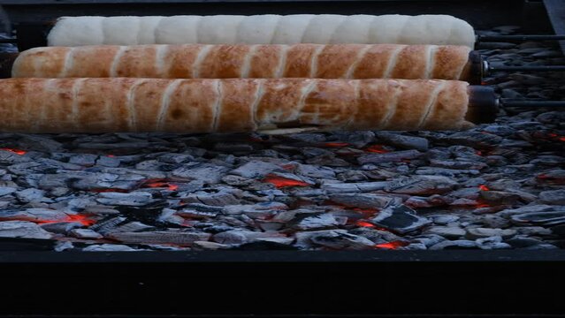 Preparation of the Hungarian traditional kurtos kalacs roasted over charcoal
