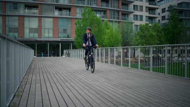 Businessman commuter on the way to work, riding bike onver bridge, sustainable lifestyle concept.
