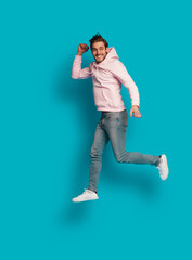 Full size photo of young happy excited smiling positive man jumping isolated on light blue color background.