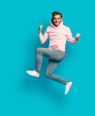 Full size photo of young happy excited smiling positive man jumping isolated on light blue color...