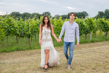 Naklejka na ściany i meble Hand in hand, the model couple swagger through the vineyards in the countryside