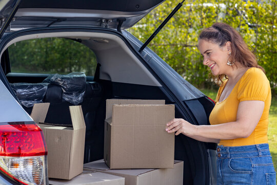 Caucasian mature woman is holding cardboard box to packing inside the car for house moving and relocation concept