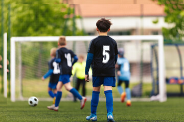 Happy Kids Playing Football Game. Sports League for Kids. Group of School Boys Kicking Soccer Tournament Match. School Boys in Soccer Jersey Kits Compete on Grass Field