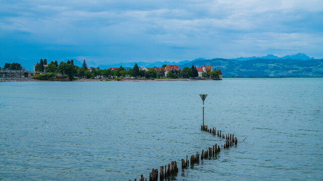 Germany, Lindau island city buildings and mountains in early morning misty atmosphere at lake constance, panorama view from water