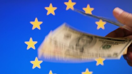 Dollar bills on EU flag background in men's hands - Powered by Adobe
