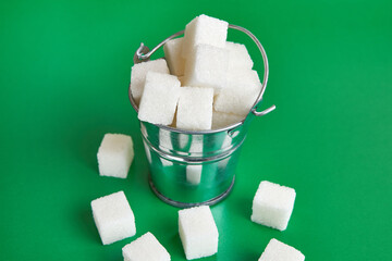 A small bucket with cubes of pressed sugar on a green background.