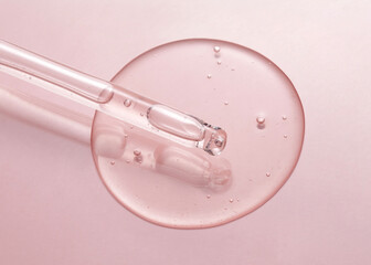 Cosmetic serum gel beauty drop and cosmetic pipette on pink color background. Skincare beauty product with bubbles texture.