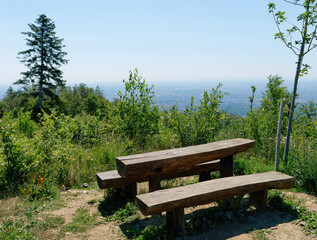 View of an old wooden bench on the top of the hill with the sky and the city in the background on a...
