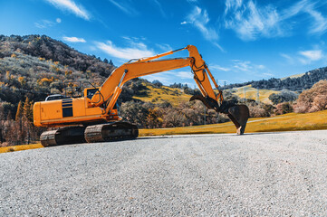 View of a yellow excavator on a rubble mound against a blue sky. Industrial screensaver.