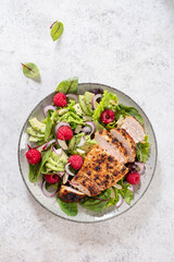Grilled chicken breast, fillet and fresh vegetable salad of lettuce, arugula, spinach, avocado, onion and pecan nut with raspberry. Summer salad, healthy eating. Fresh healthy food.