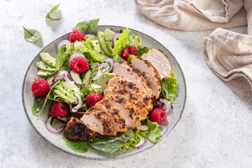 Grilled chicken breast, fillet and fresh vegetable salad of lettuce, arugula, spinach, avocado, onion and pecan nut with raspberry. Summer salad, healthy eating. Fresh healthy food.