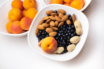 A delicious healthy snack during the day - nuts, apricots and black blueberries, top view. Healthy ecological food