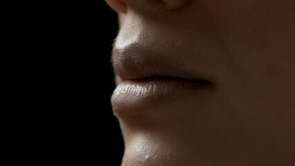 Extreme close-up shot of young African American female model's lips on black background | Lips care concept