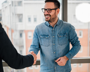 Excited business professionals sealing and closing successful deal with handshake at office.