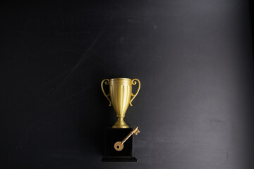 trophy and key against chalkboard
