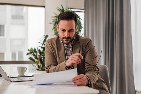 Business accountant bookkeeper in office looking at documents and working with laptop.