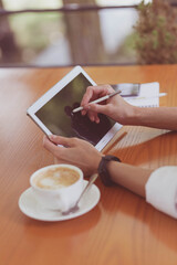 Portrait happy young office assistant working remotely online sitting with laptop, tablet and coffee outside on terrace making notes on laptop and checking smartphone. Remote freelance successful job