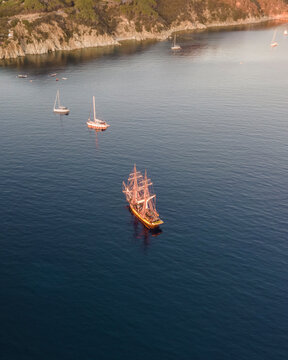 Aerial view of a pirate vessel sailing along the coast at sunset in Capo D'Enfola, Elba Island, Tuscany, Italy.
