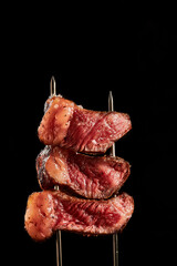 primer plano de picanha con unas pinzas enun fondo negro