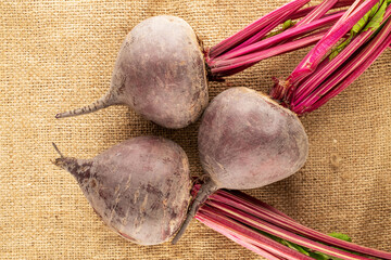 Three sweet red beetroots on jute fabric, close-up, top view.