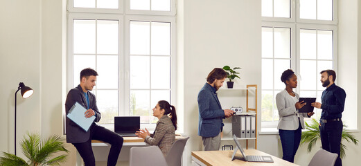 Office interior in which various busy colleagues talk, discuss and solve work matters. Each of the business team performs its work. Coworking concept. Panoramic web banner.