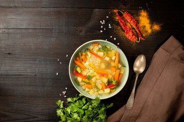 Homemade vegetable soup, overhead view on a dark wooden background