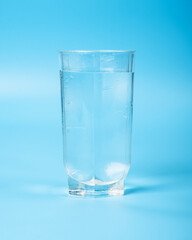 clean water in a glass beaker closeup on a blue background.