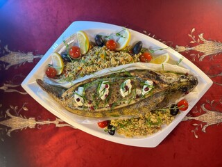 whole fish baked pike perch on a white platter is served in the restaurant