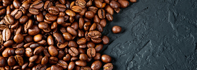 Roasted coffee beans on a black background. Copy space. Flat lay. Banner