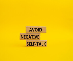 Avoid negative self-talk symbol. Concept words Avoid negative self-talk on wooden blocks. Beautiful yellow background. Business and Avoid negative self-talk concept. Copy space.