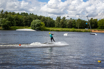 Wakeboarder on wakeboard landed in water surrounded by spray. A man rides water skis at high speed....