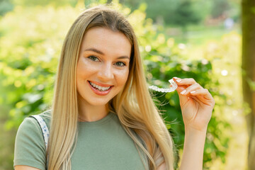 Woman with a perfect charm smile holds a removable night retainer. Bracket for teeth whitening.