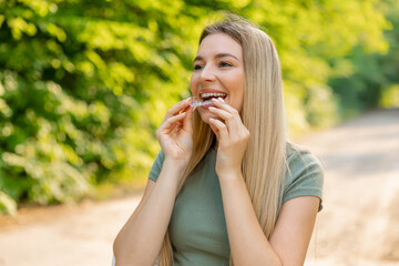 Happy woman holding an invisible teeth aligner while smiling