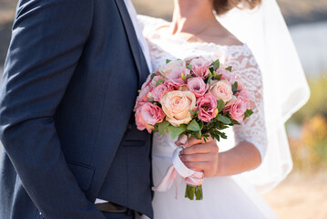 wedding bouquet of roses in the hands of the bride and groom. floristry for the holiday