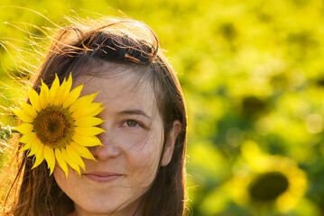 Girl in the yellow Sunflower Fields Young woman laughs with a sunflower on her face copy space